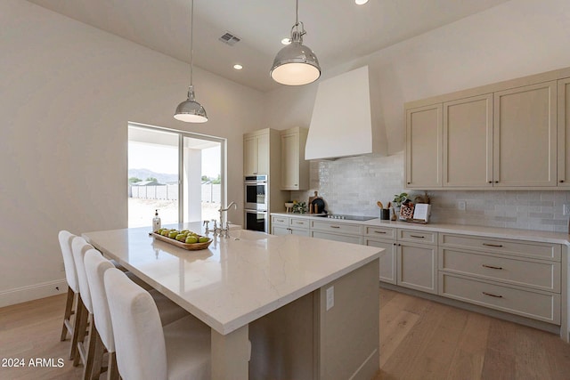 kitchen featuring custom range hood, pendant lighting, a kitchen island with sink, and black electric cooktop