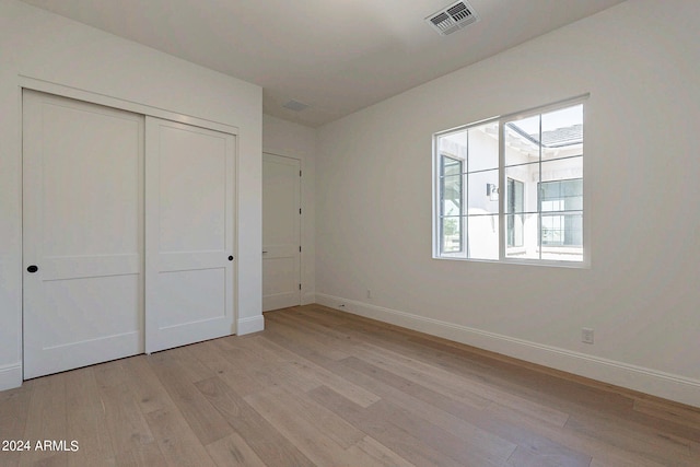 unfurnished bedroom with light wood-type flooring and a closet