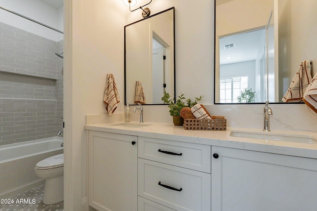 full bathroom featuring dual vanity, tiled shower / bath, and toilet