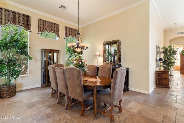 dining area featuring a high ceiling, ornamental molding, and a chandelier