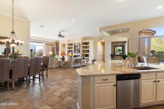 kitchen with light stone countertops, pendant lighting, dishwasher, sink, and a kitchen island with sink