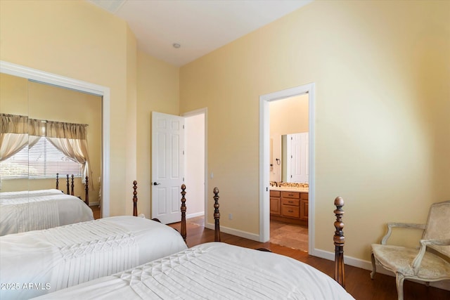 bedroom featuring dark hardwood / wood-style flooring, ensuite bath, and a towering ceiling