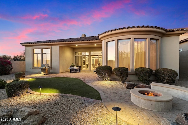 back house at dusk with a fire pit and a patio