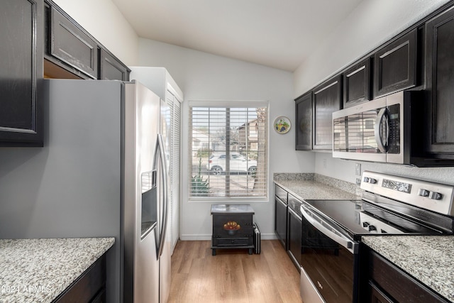 kitchen featuring light stone counters, light wood-type flooring, vaulted ceiling, and appliances with stainless steel finishes