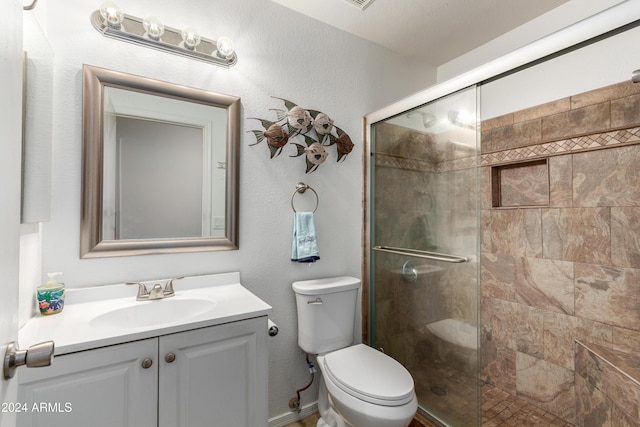 bathroom with a shower with door, vanity, and toilet