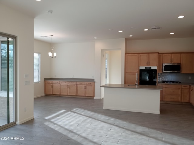 kitchen featuring black appliances, a center island with sink, sink, hanging light fixtures, and a chandelier