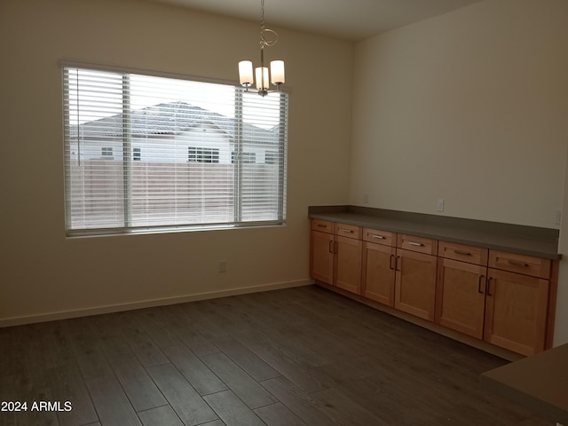 unfurnished dining area with dark hardwood / wood-style floors and an inviting chandelier