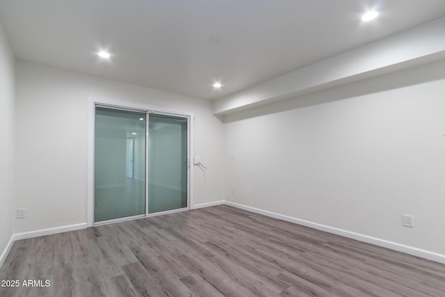 spare room featuring recessed lighting, wood finished floors, and baseboards