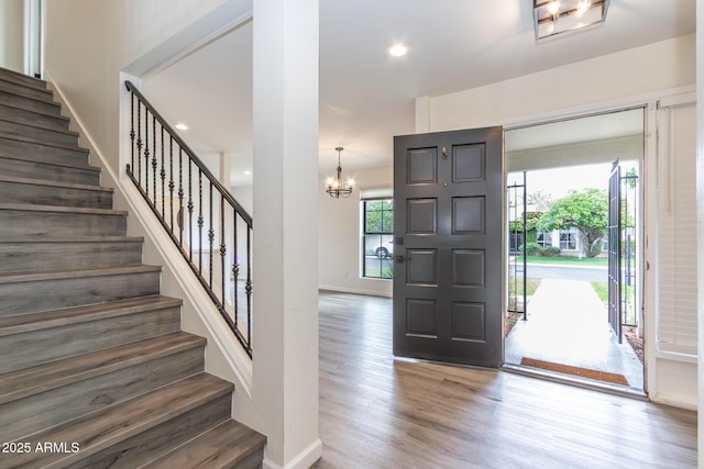 foyer with wood finished floors, baseboards, recessed lighting, stairs, and a chandelier