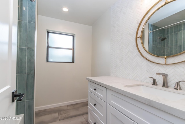 full bath featuring tasteful backsplash, baseboards, recessed lighting, tiled shower, and vanity