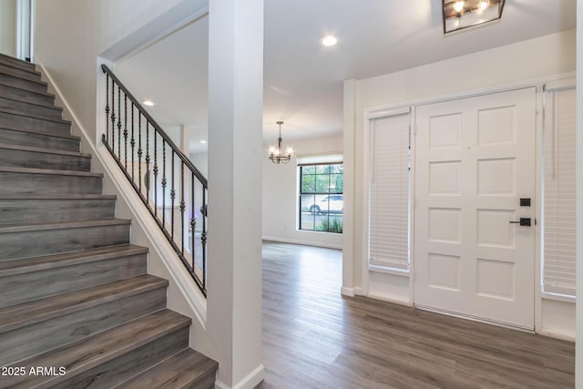 foyer with wood finished floors, recessed lighting, baseboards, a chandelier, and stairs