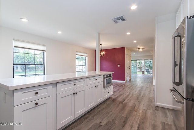 kitchen with stainless steel appliances, white cabinetry, visible vents, and light countertops