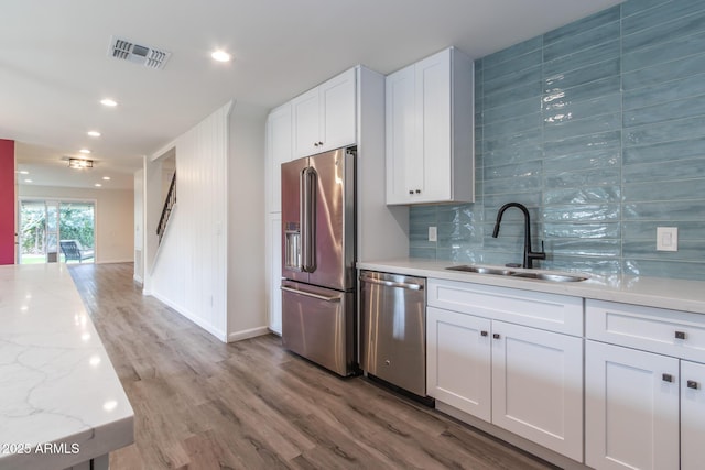 kitchen with visible vents, a sink, tasteful backsplash, white cabinetry, and stainless steel appliances