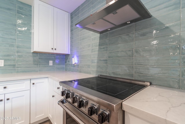 kitchen with high end range, white cabinetry, extractor fan, and light stone countertops