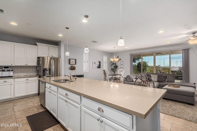 kitchen with stainless steel appliances, backsplash, open floor plan, white cabinets, and a sink