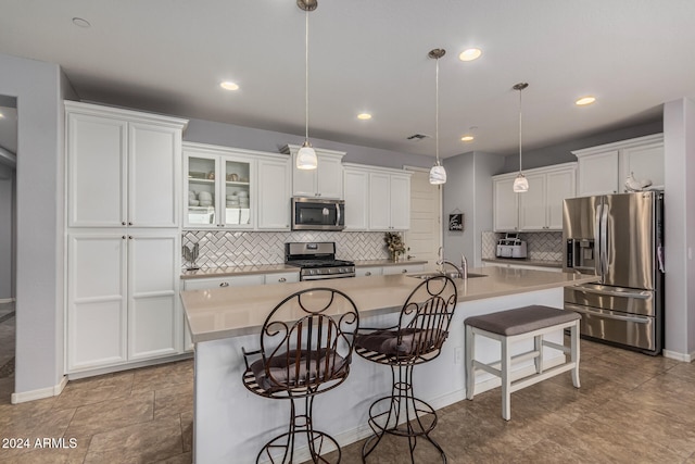 kitchen with stainless steel appliances, white cabinetry, a sink, and a kitchen bar