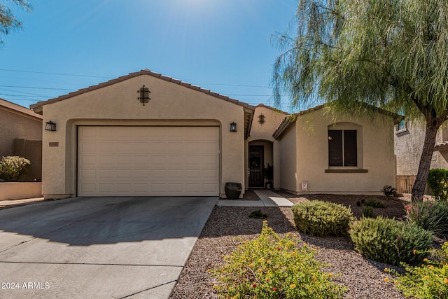 mediterranean / spanish-style home featuring driveway, an attached garage, a tiled roof, and stucco siding