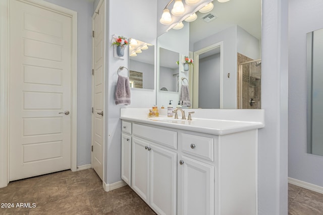 bathroom with vanity, a tile shower, visible vents, and baseboards