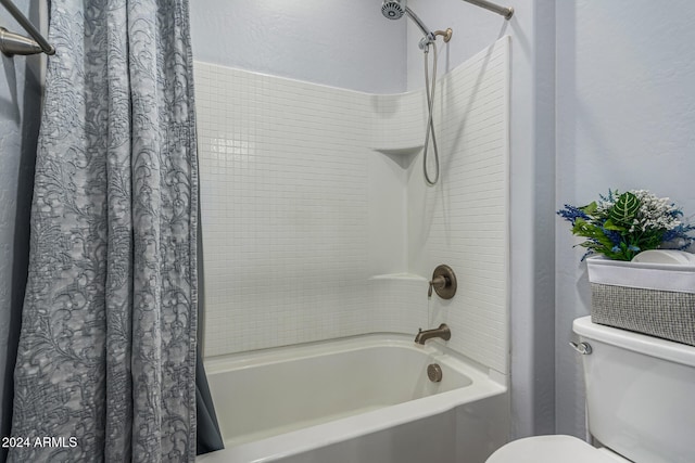 bathroom featuring shower / bath combination with curtain, a textured wall, and toilet