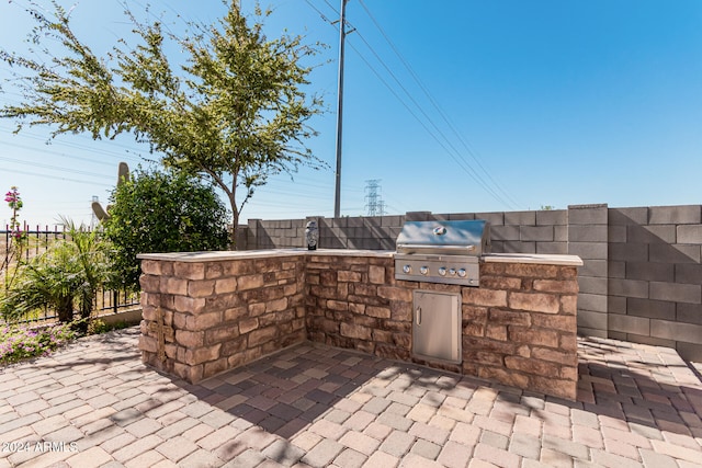 view of patio with area for grilling, an outdoor kitchen, and a fenced backyard