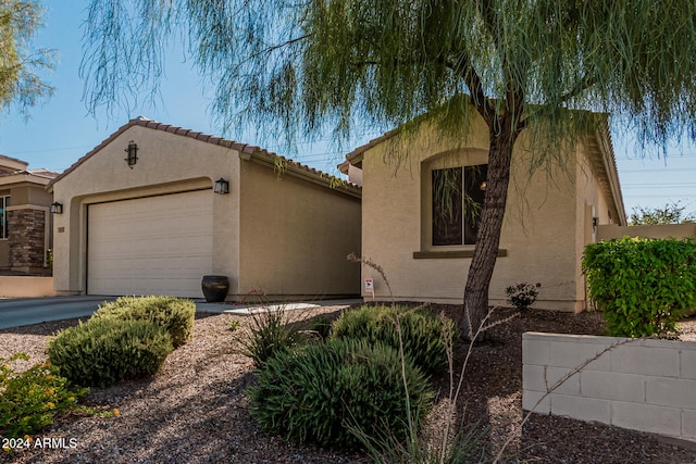 view of front of property featuring an outdoor structure, a tiled roof, an attached garage, and stucco siding