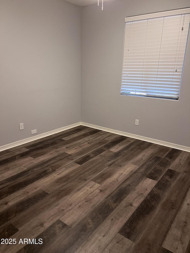 empty room featuring baseboards and dark wood-type flooring