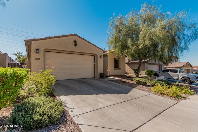 view of front of home featuring an attached garage, fence, concrete driveway, a tiled roof, and stucco siding