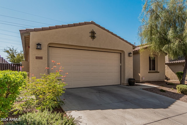 exterior space featuring a tiled roof, an attached garage, driveway, and stucco siding