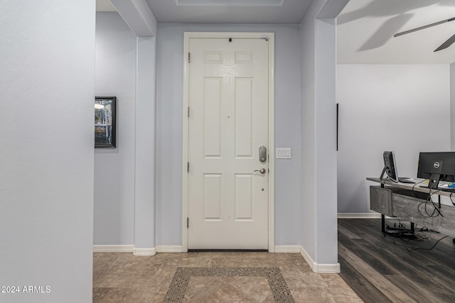 foyer with wood finished floors, a ceiling fan, and baseboards