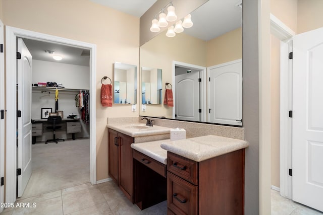 bathroom with vanity, baseboards, tile patterned flooring, and a spacious closet
