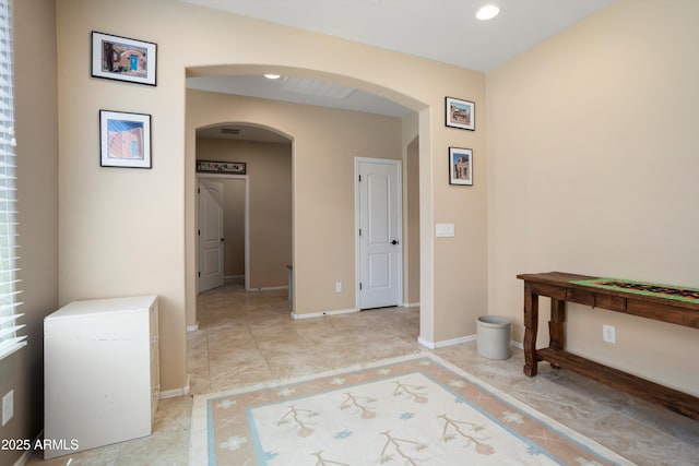 hall featuring arched walkways, baseboards, and recessed lighting