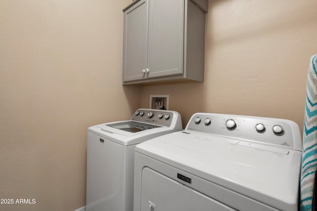 clothes washing area featuring independent washer and dryer and cabinet space