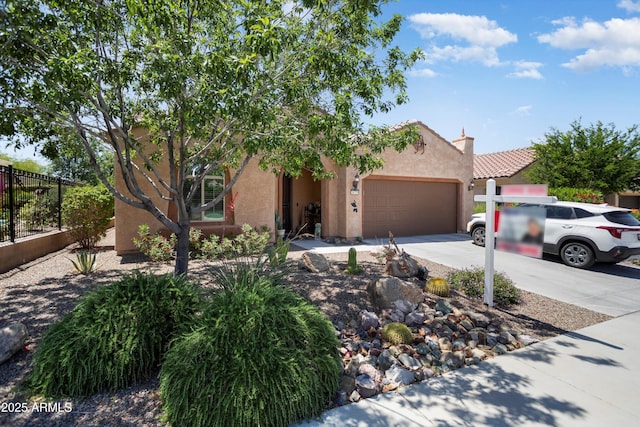 view of front of house with fence, stucco siding, an attached garage, driveway, and a tile roof