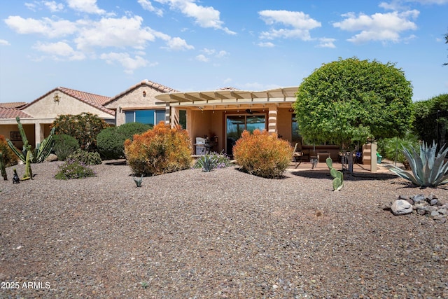 view of front facade featuring a patio, stucco siding, a pergola, and a tiled roof