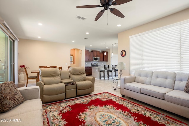 living area featuring arched walkways, ceiling fan, recessed lighting, and visible vents