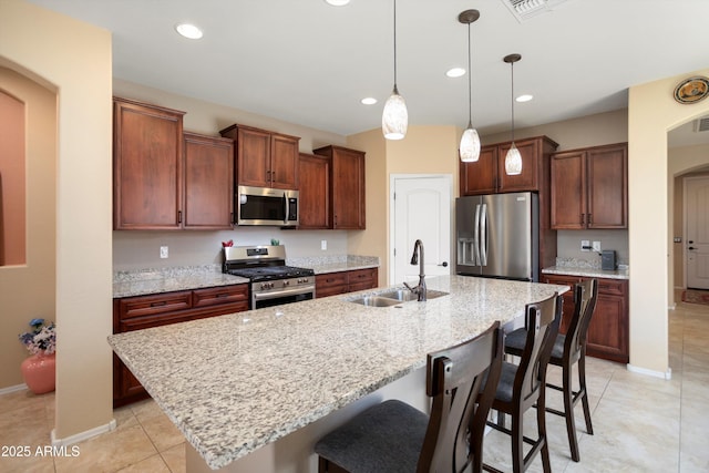 kitchen featuring a kitchen breakfast bar, appliances with stainless steel finishes, arched walkways, a sink, and light tile patterned floors