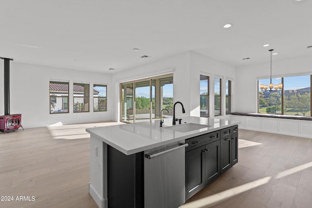 kitchen featuring dishwasher, an island with sink, sink, hanging light fixtures, and an inviting chandelier