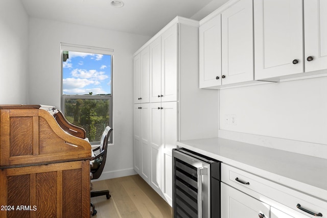 interior space featuring beverage cooler, light hardwood / wood-style floors, and white cabinets