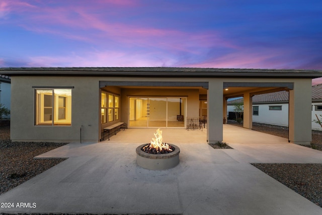 back house at dusk with a patio area and a fire pit