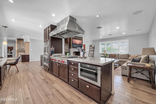 5621 N 13th St, Phoenix, AZ 85014 - kitchen featuring stainless steel appliances, island exhaust hood, light wood-style flooring, dark brown cabinetry, and recessed lighting