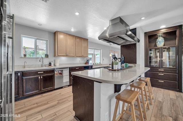 5621 N 13th St, Phoenix, AZ 85014 - kitchen with appliances with stainless steel finishes, island exhaust hood, a breakfast bar area, light wood-type flooring, and recessed lighting