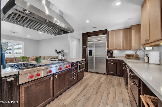 5621 N 13th St, Phoenix, AZ 85014 - kitchen featuring stainless steel appliances, exhaust hood, light countertops, light wood-style flooring, and recessed lighting