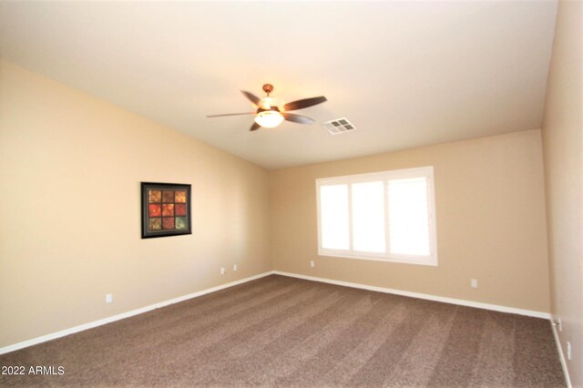 spare room with vaulted ceiling, ceiling fan, and dark colored carpet