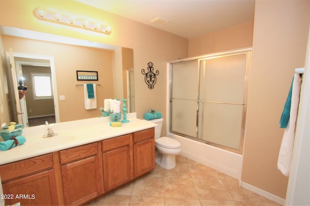 full bathroom featuring tile floors, vanity with extensive cabinet space, bath / shower combo with glass door, and toilet