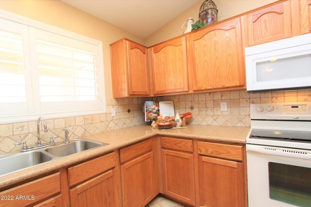 kitchen with white appliances, sink, tasteful backsplash, and lofted ceiling