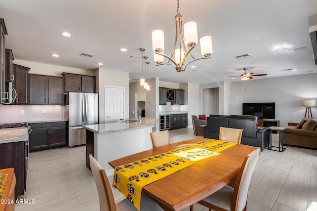 dining space featuring ceiling fan with notable chandelier, sink, and wine cooler