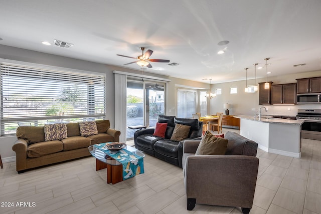 living room with sink and ceiling fan with notable chandelier