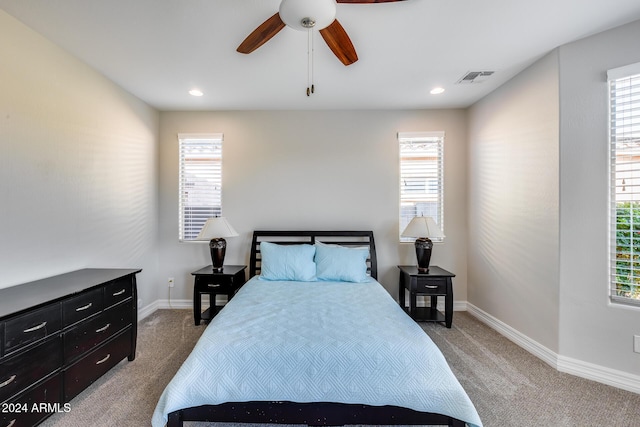 bedroom with ceiling fan, light carpet, and multiple windows