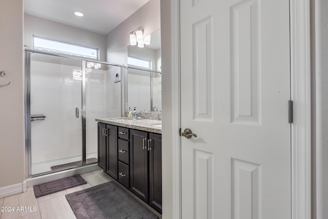 bathroom featuring a shower with door and vanity