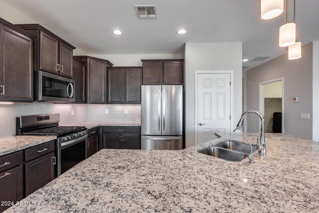 kitchen featuring sink, tasteful backsplash, pendant lighting, dark brown cabinets, and appliances with stainless steel finishes